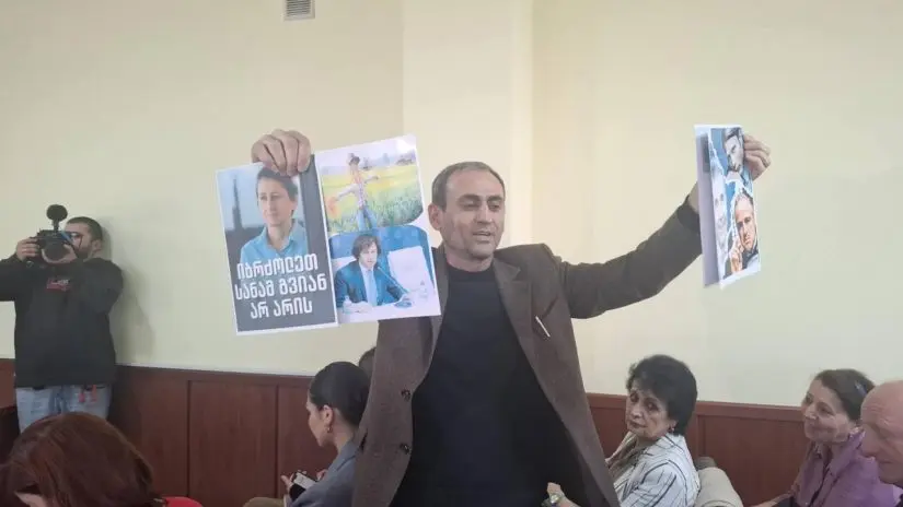 ბათუმში მზია ამაღლობელის სასამართლო პროცესზე აზერბაიჯანელი ჟურნალისტი აფგან სადიგოვი საპროტესტო ბანერებით მივიდა