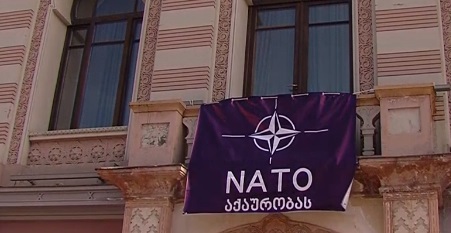 "პატრიოტთა ალიანსის" აქციის ფონზე პლაკატი "NATO აქაურობას" გამოჩნდა